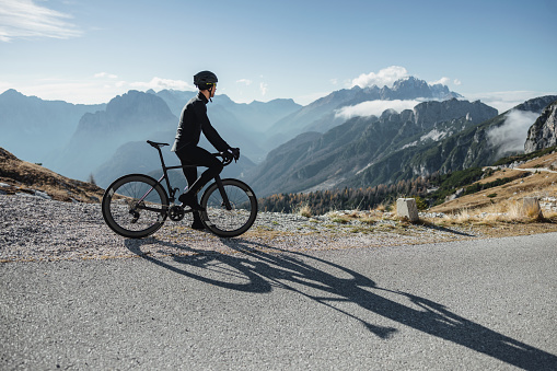 A photo showcases a recreational cyclist on a mountainous road, dressed in his cycling gear, helmet, and gloves. The focus is on his strong physical condition, highlighting his dedication to staying healthy through cycling.