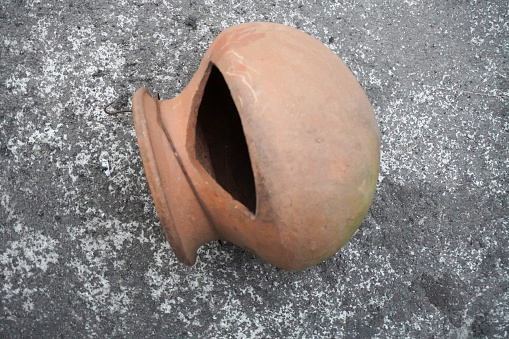 Old empty round red clay bowl. Round clay cup. Top view of clay bowl on a floor background. Clay bowls on concrete floor