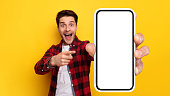 Shocked guy pointing at white empty smart phone screen