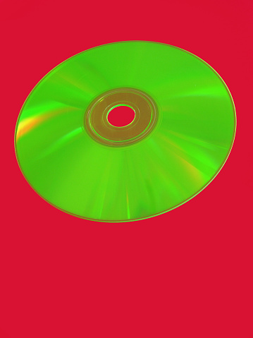 Shiny green compact disc over red background