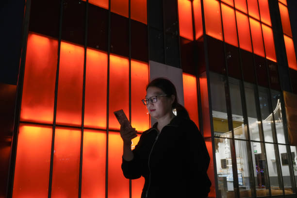 istock Asian woman using cell phone against red background 1480800409