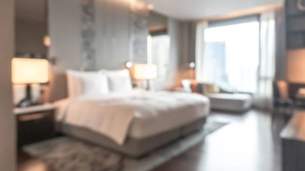 istock Hotel bedroom blur background guest room interior with blurry comfortable king size bed white, bedsheet, TV, work table desk and chair furniture 1480802014