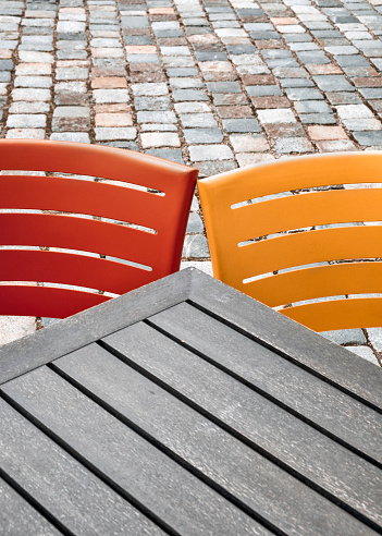 An orange and yellow chait behind a wooden table.