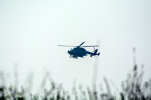 Combat helicopter is flying against isolated blue sky. Combat helicopter attack enemy.