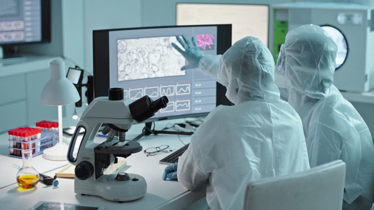 Scientist, lab analysis and computer with hazmat team, ppe and medical research for virus cure. Science group, safety suit and people with pc in laboratory for data analytics with microscope in study