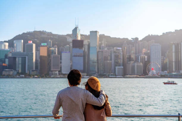 Young couple traveler relaxing and enjoying the sunset atmosphere at Victoria harbour in Hong Kong stock photo