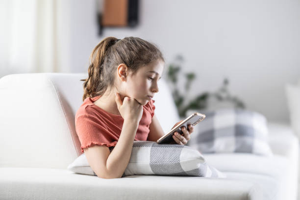 Young generation always on their phones represented by a girl at home with a cellphone in her hand. stock photo
