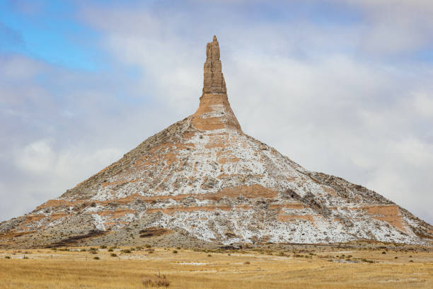 Chimney Rock National Monument Nebraska early morning winter landscape with a dusting of snow, blue sky and clouds.