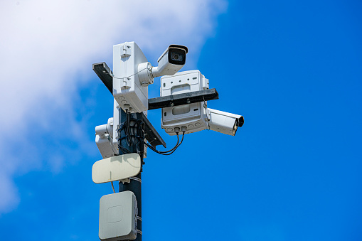Security CCTV surveillance cameras against blue sky with clouds