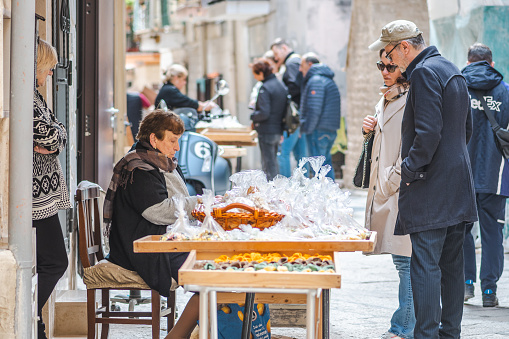 Bari, Italy - April 5 2023: Elderly woman selling to tourists fresh orecchiette or orecchietta in Bari old town, made with durum wheat and water, handmade pasta typical of Puglia or Apulia, a region of Southern Italy