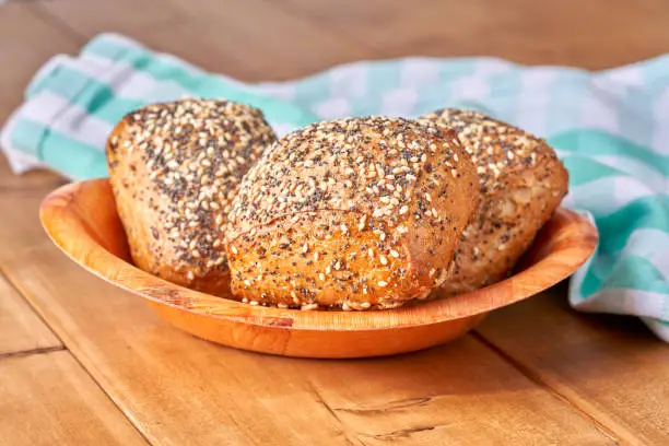 Bun with poppy seeds and sesame on the wooden table.