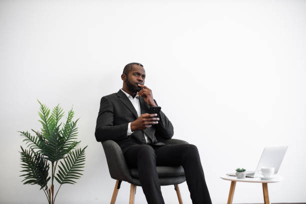 istock Pensive man in suit sitting at office and using smartphone 1480826212