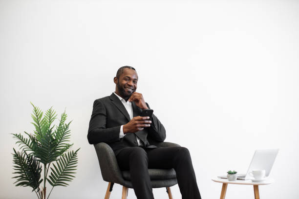 istock African man smiling at camera and using smartphone at office 1480826232