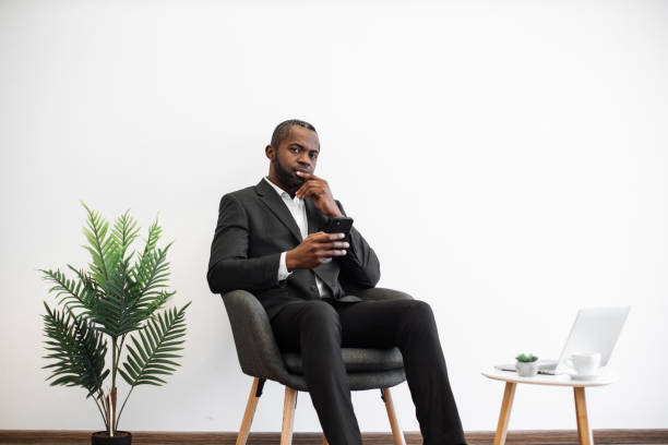 istock Pensive man in suit sitting at office and using smartphone 1480826236