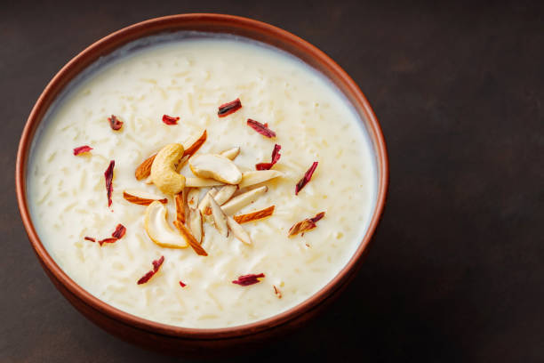 istock Creamy rice Kheer garnished with nuts and hibiscus. Bowl with rice pudding on dark background. Top view 1480826661