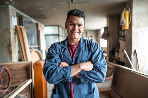 Portrait of a young carpenter with arms crossed at carpentry