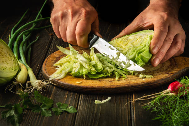 istock Slicing cabbage on a cutting board. Delicious salad for dinner with fresh vegetables. Hands of a chef with a knife while cooking in a kitchen. 1480830376