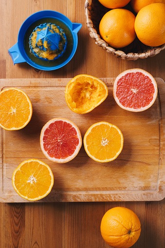 Halved oranges and grapefruits on a wooden cutting board, table top view