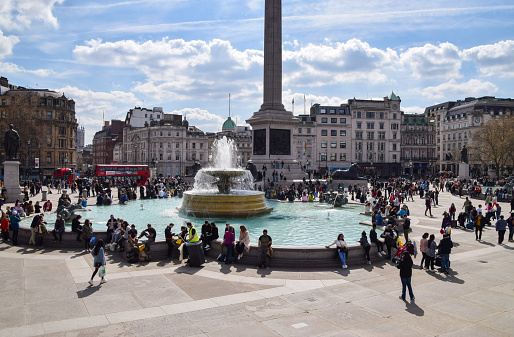 London, UK - April 8 2023: People enjoy the sunshine around the fountains in Trafalgar Square on a warm spring day.