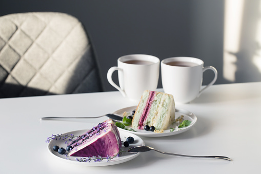 berry cheesecakes and two cups of tea on  white table on background gray wall