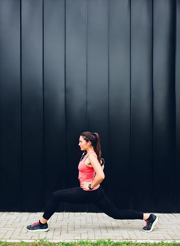 Beautiful young woman doing exercises in front of a black wall