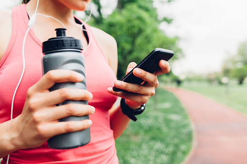 Closeup of sporty woman using smart phone after running