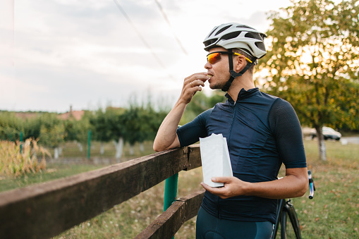 Professional cyclist in cycling gear taking a break and eating a snack