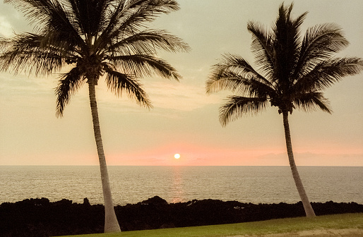 Film photograph of a vibrant Hawaiian volcanic orange sunset over the ocean horizon.