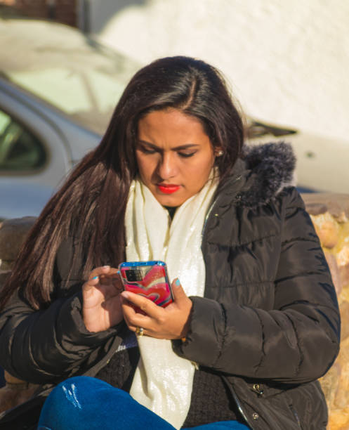 istock Woman in a park sitting and checking her cell phone 1480850144