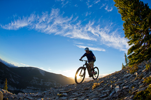A male rider and his e-bike mountain bike or electric mountain bicycle in the Rocky Mountains of Canada.