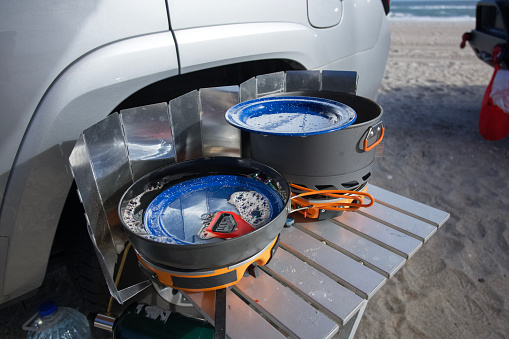 Brush and plates in camping stove in beachside campsite