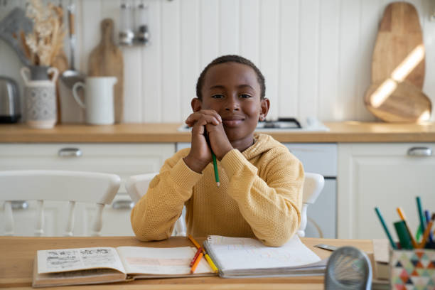 istock Happy portrait of smiling Black content boy study at home with textbook. Successful homeschooling. 1480854363