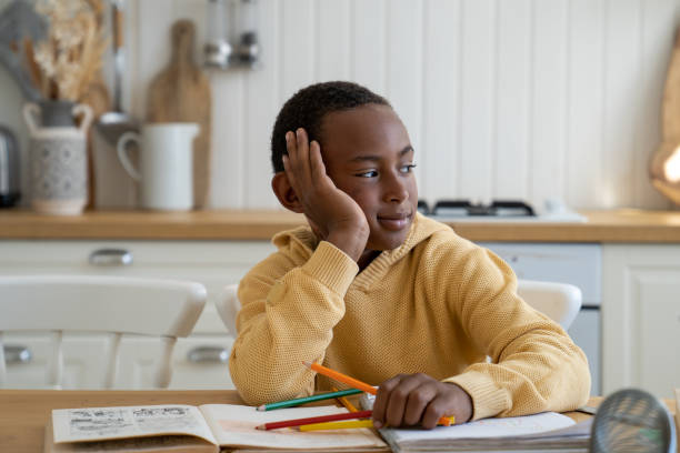 istock Cute pensive biracial child boy look side at window distracted from study dream about computer game 1480854375