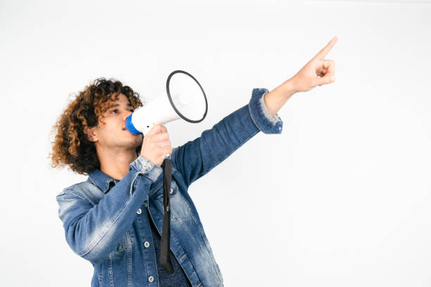 joven sosteniendo un megáfono mientras posa contra un fondo blanco - american justice audio fotografías e imágenes de stock