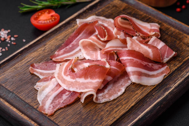 deliciosa panceta fresca con sal y especias cortada en finas rodajas - pancetta fotografías e imágenes de stock