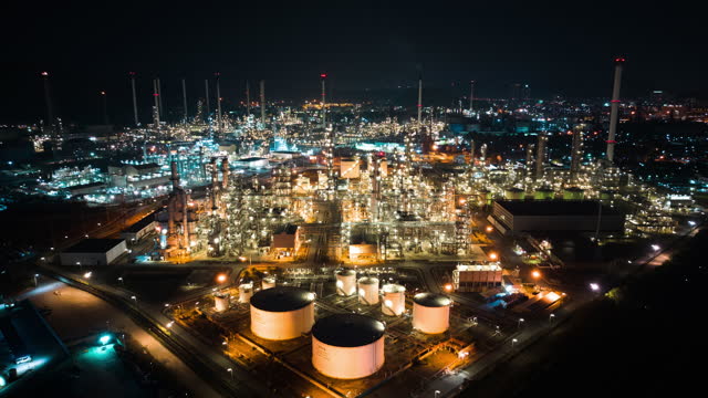 Hyperlapse time lapse of petroleum oil refinery in industrial estate at night, drone aerial view. Fuel and power generation, petrochemical factory industry, or environmental air pollution concept