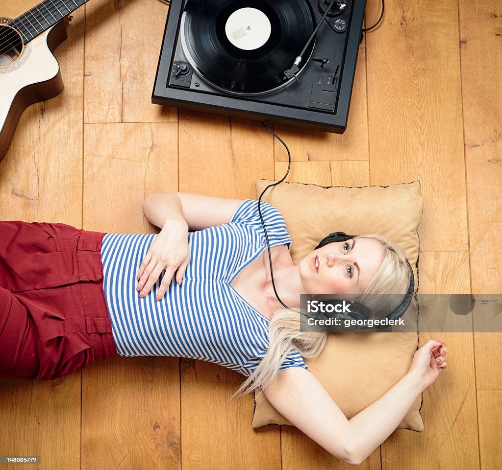 Young Woman Listening to a Record A woman listening to a record with headphones. Turntable Stock Photo