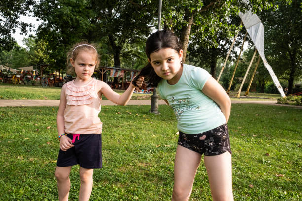 Two girls holding hands and swinging each other around.