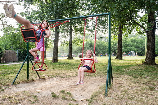 little girls are swinging on the swing in playground