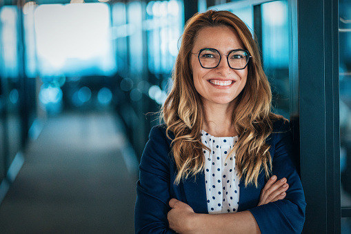 Confident businesswoman at her workplace at modern office. Portrait of businesswoman happily smiling and looking at camera