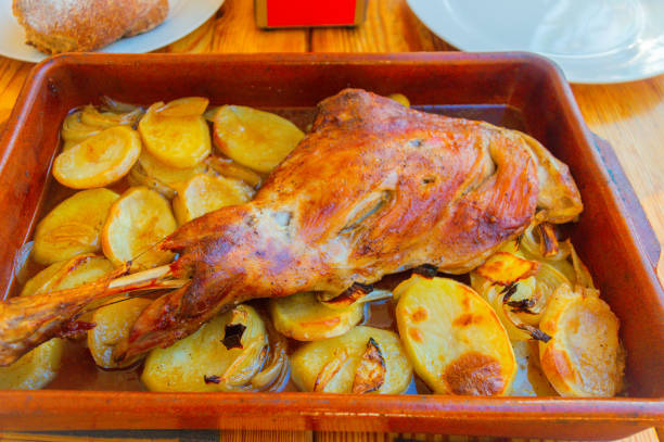 Roast leg of lamb in the oven with potatoes in a clay tray