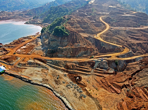 middle Sulawesi, Indonesia - August 09 2021: Drone view mine hauling road nickel, stockpiling and creation of a new EFO, excavator and dumbstruck loading quarry and moving ore material from Pit to EFO