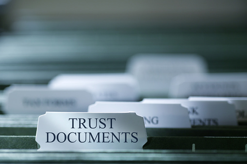 A file folder containing trust documents photographed with a very shallow depth of field.