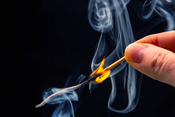 istock Flashed and burning wooden match on a dark background close-up. Bright fire and smoke from a burning tree. 1480874702