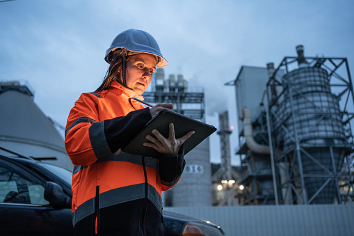 Female working late with tablet in a power plant.