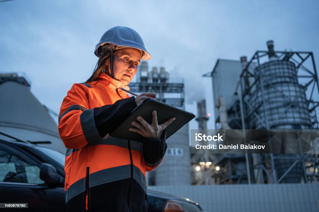 Woman engineer working in power plant, night shift. Female working late with tablet in a power plant. Maintenance Engineer Stock Photo