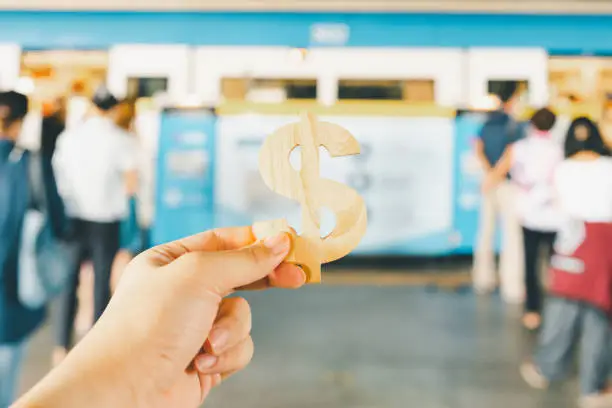 Photo of Hand 's holding Dollar sign on the train with blur people background. The concept of urban commuting expenses.