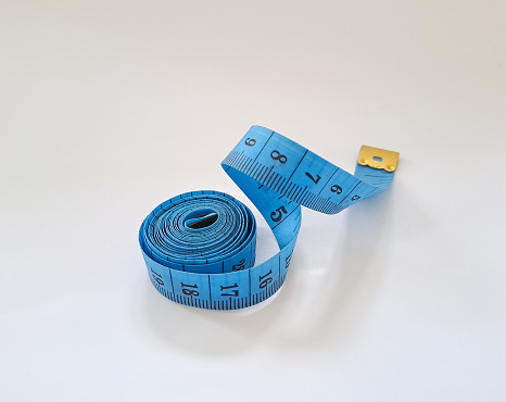 Close-up of a blue tape measure on a gray background. Shallow depth of field, space for copy.