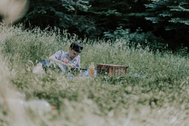 jovem moreno em um piquenique na floresta. - men reading outdoors book - fotografias e filmes do acervo