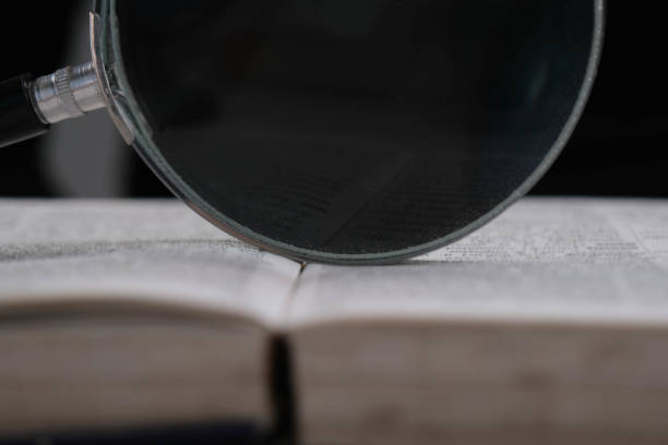 Magnifying glass over open book on table. Education and research concept.